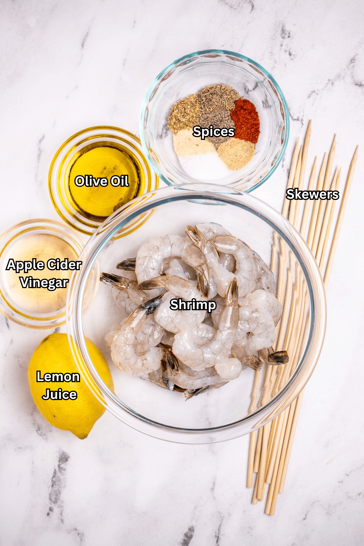 Individual ingredients for grilled shrimp skewers on a table.