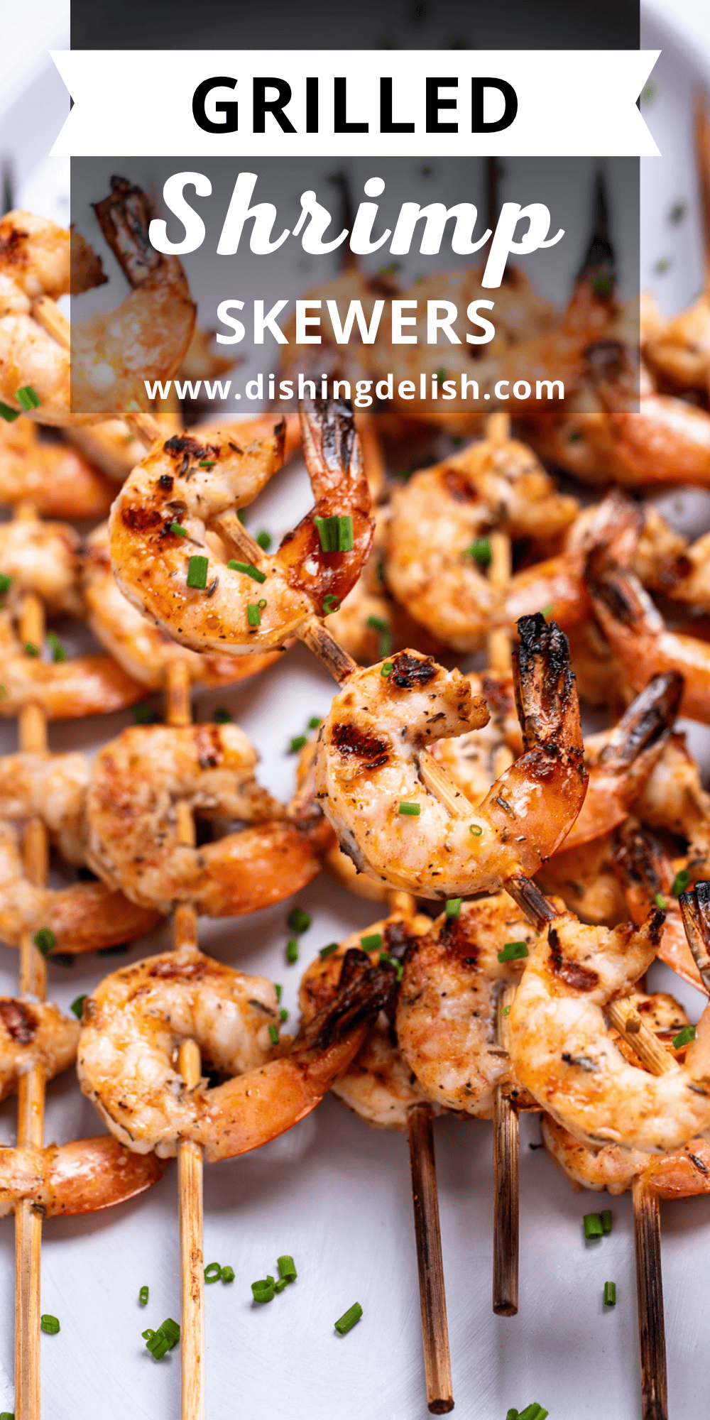 Pinterest pin with a plate on a table with grilled shrimp skewers topped with green onion, and one being held up.
