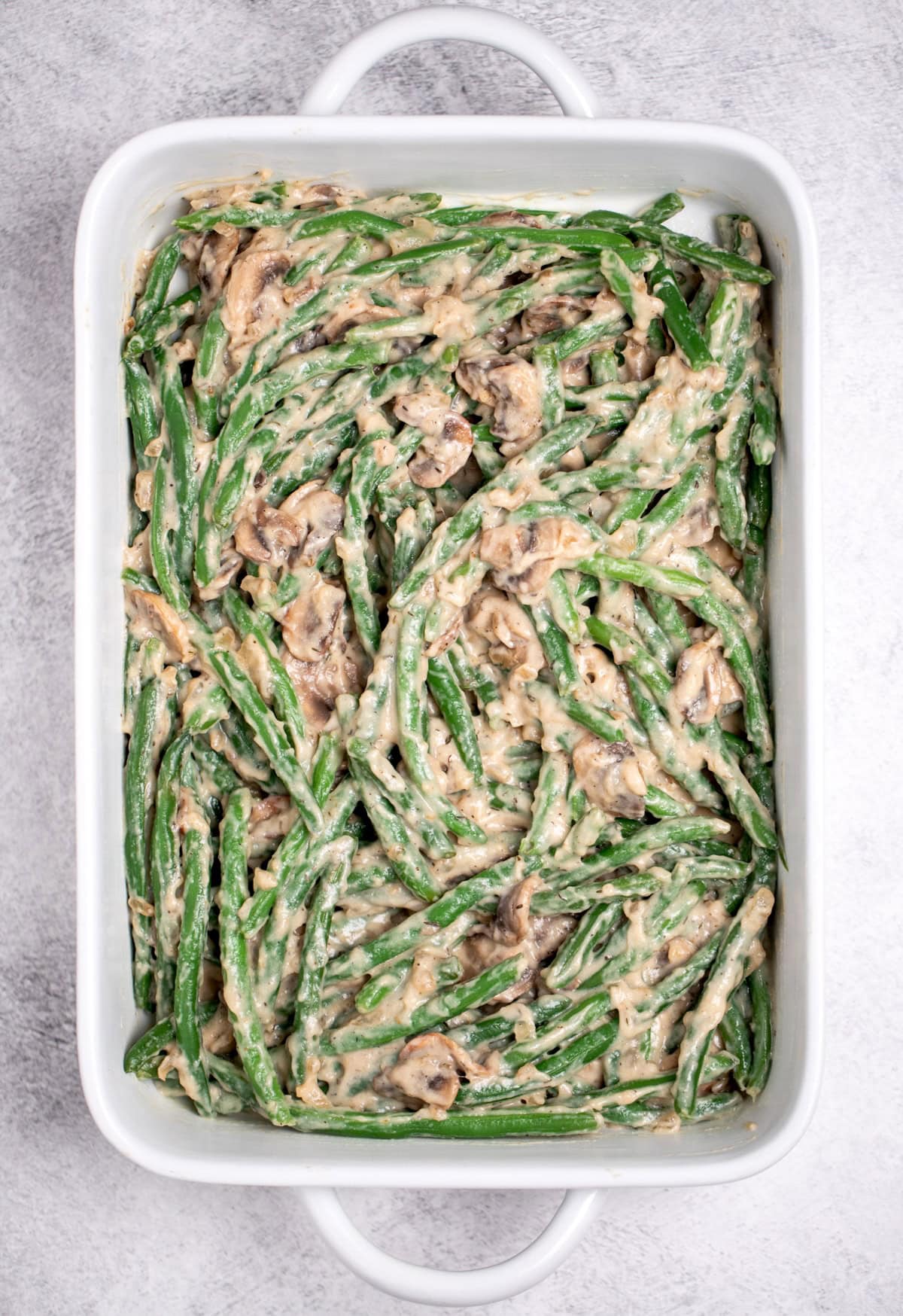 A casserole dish with green beans mixed with mushroom sauce, before being baked.