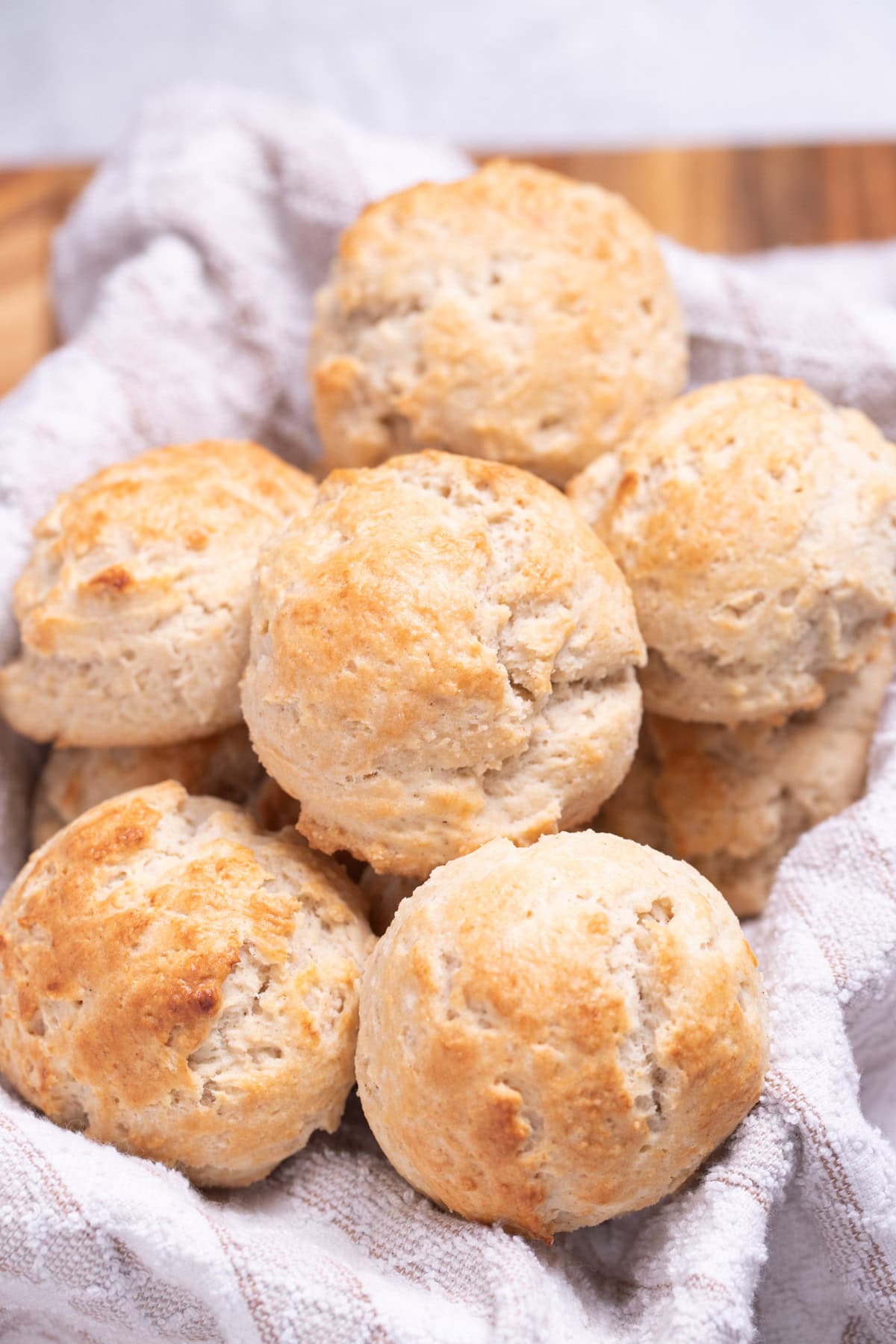A basket with a tea towel full of gluten free drop biscuits resting on top of each other.