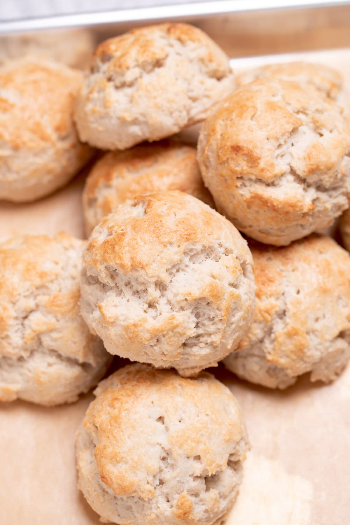 A pile of gluten free drop biscuits on a baking sheet lined with parchment paper.