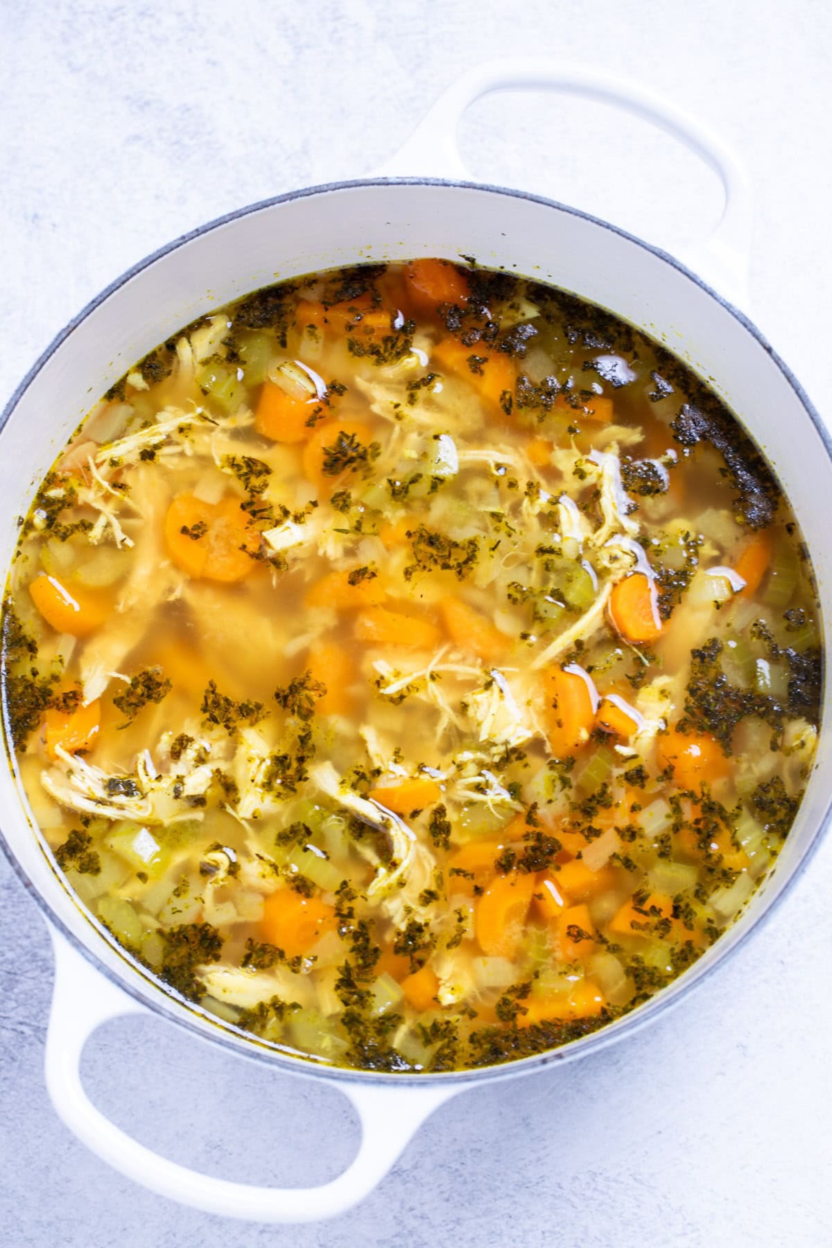A dutch oven full of chicken noodle soup before adding the noodles.
