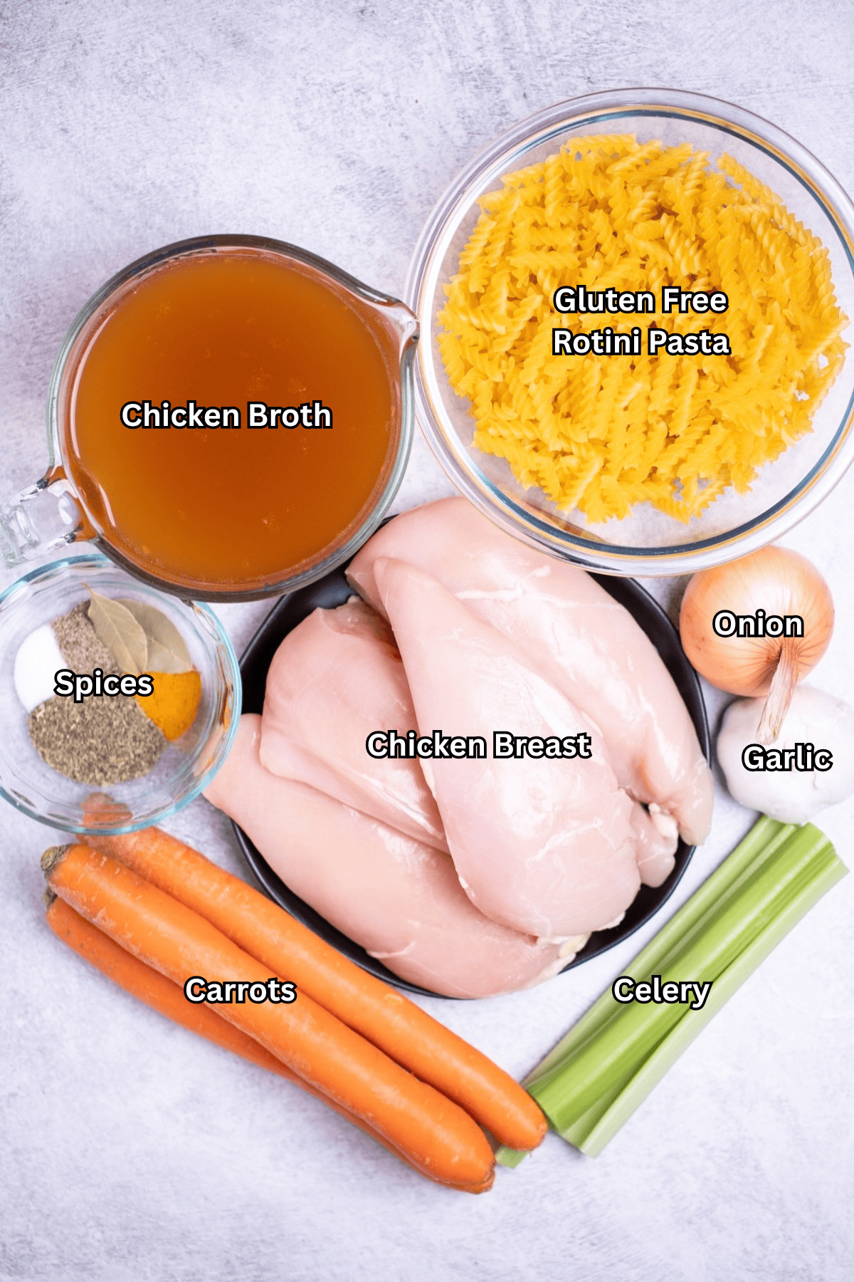 Individual ingredients for gluten free chicken noodle soup on a table.