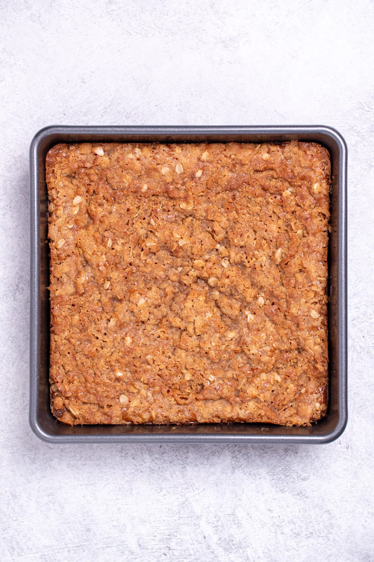 A baking dish of pumpkin crisp on a table, before being cut into.