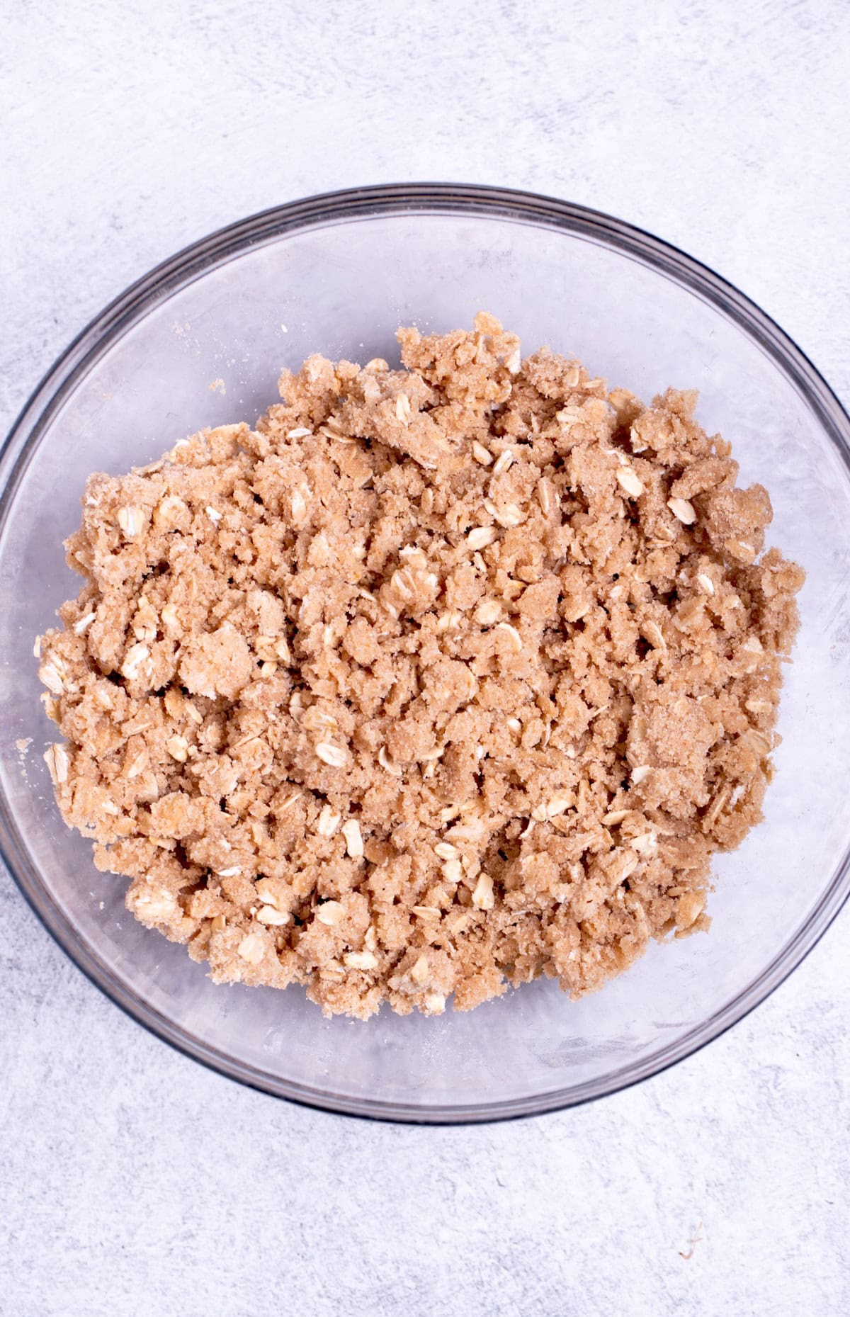 A mixing bowl with the oat streusel topping mixed with butter, before being added to the crisp.