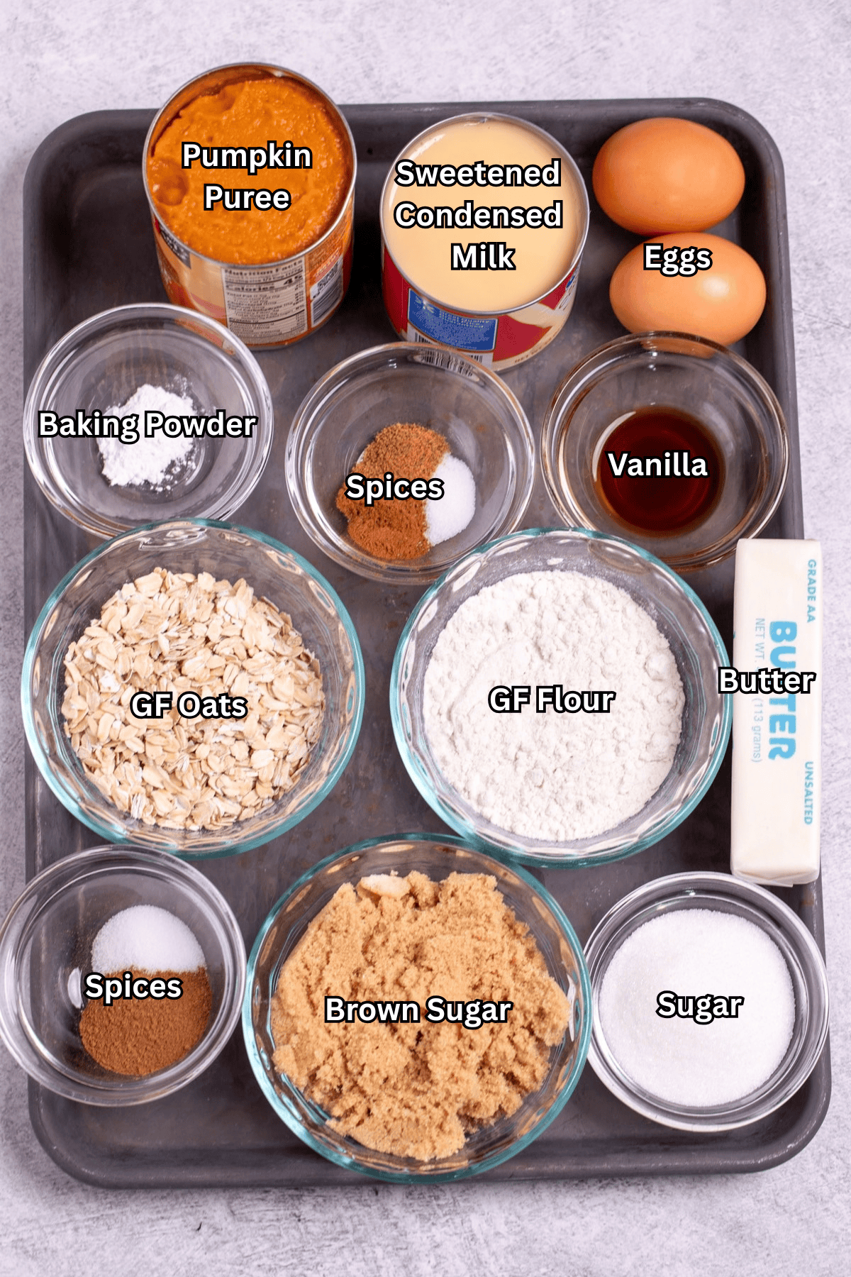 Individual ingredients for pumpkin crisp on a sheet pan, on a table.