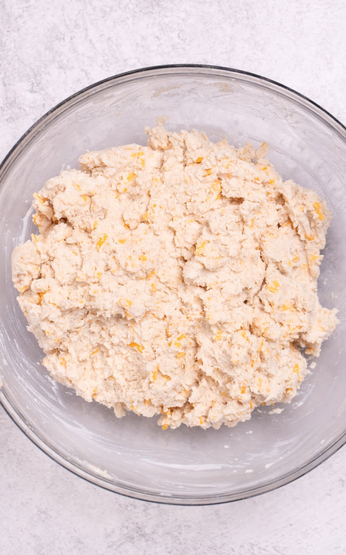 A mixing bowl on a table with cheddar bay biscuit dough before being scooped.