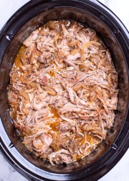 A slow cooker full of shredded apple cider pulled pork.