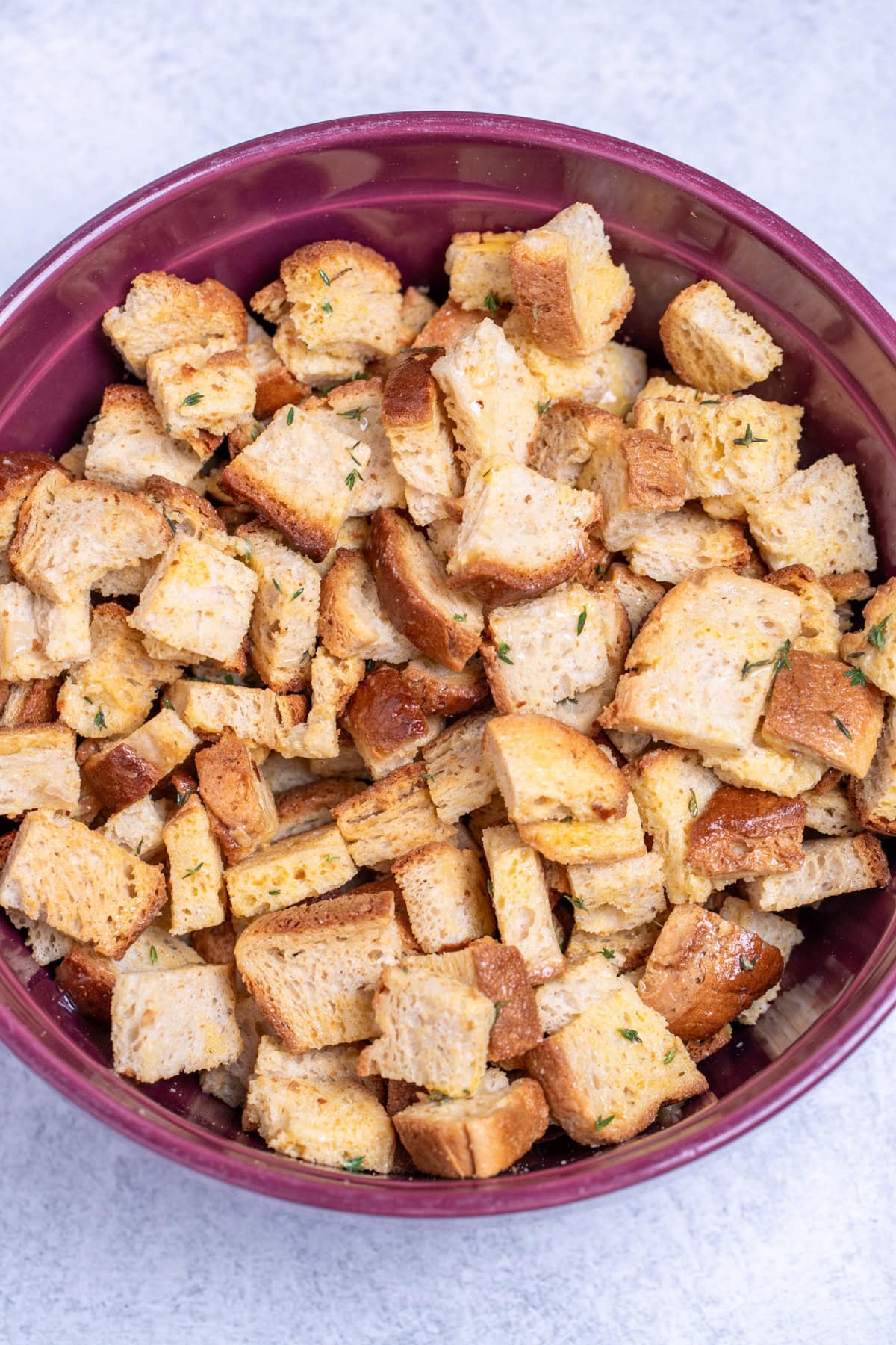 A bowl on a table with toasted gluten free bread cubes coated in egg and seasoning.