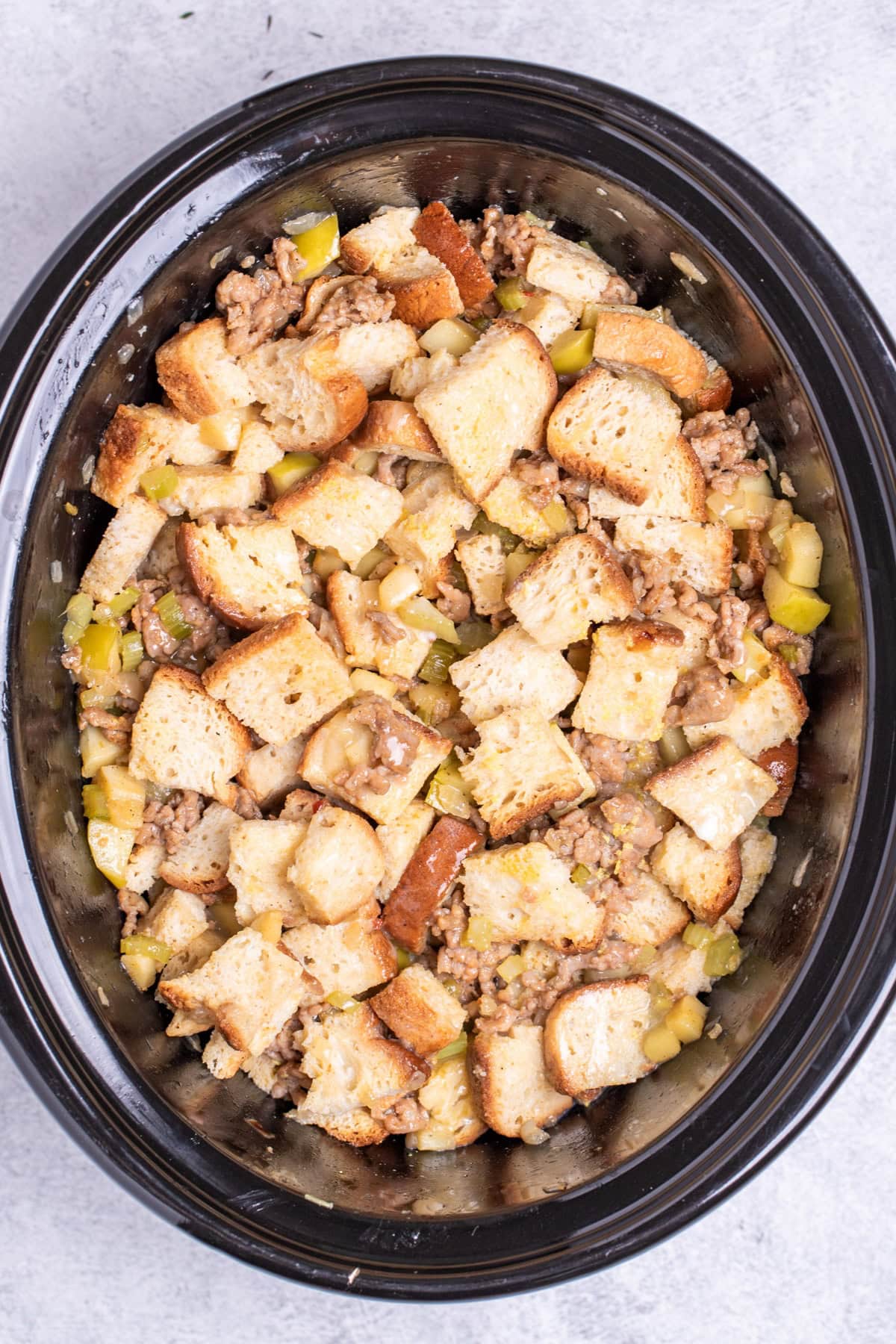 A slow cooker full of gluten free sausage stuffing before being cooked.